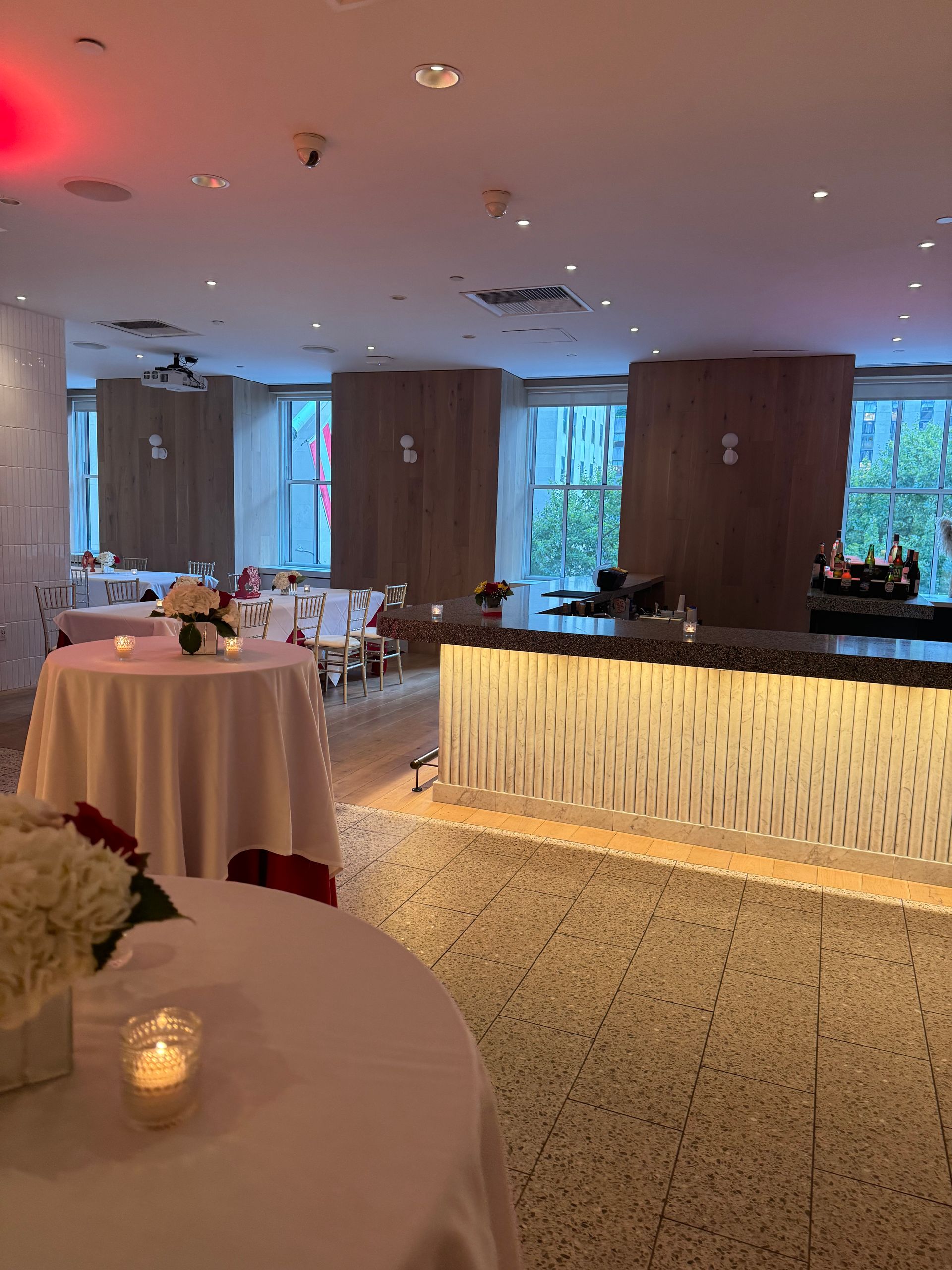 A large room with tables and chairs and a bar.