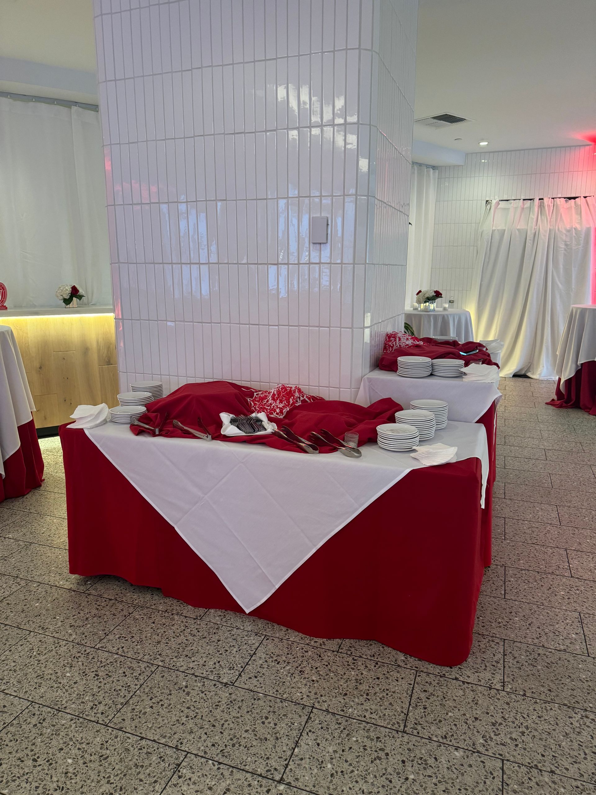 A buffet table with red and white tablecloths in a room.