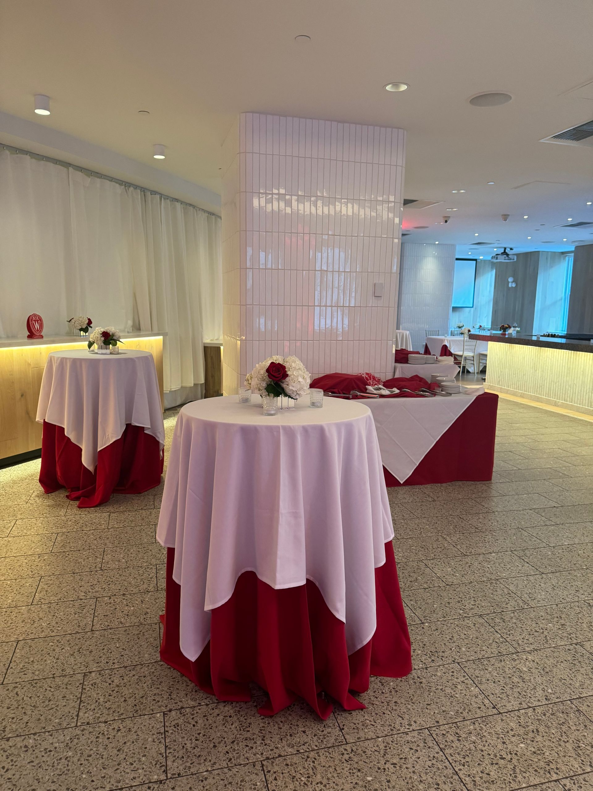 EQX City Catering at Rockefeller Center. A room filled with tables and chairs with red and white tablecloths.
