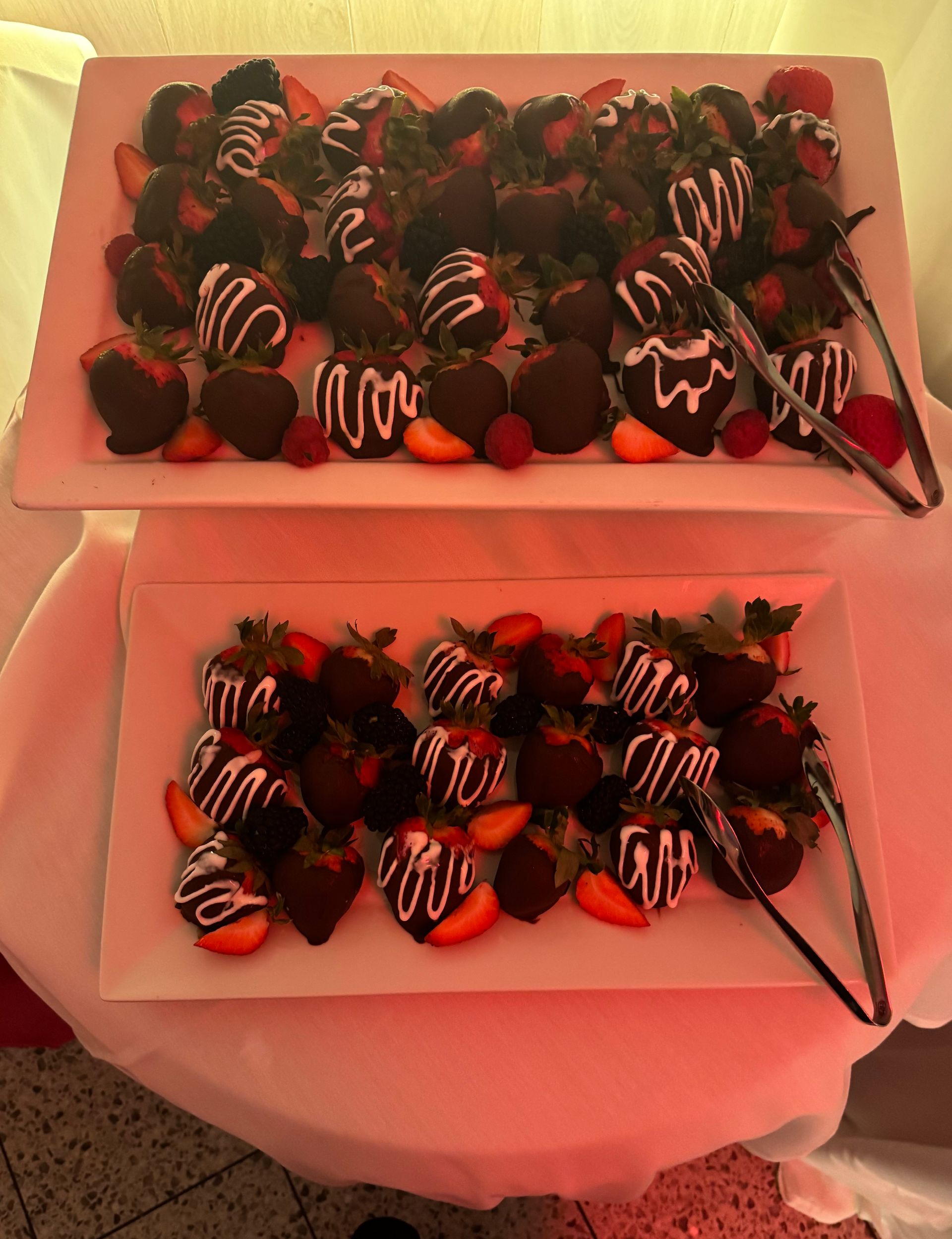 Two trays of chocolate covered strawberries on a table