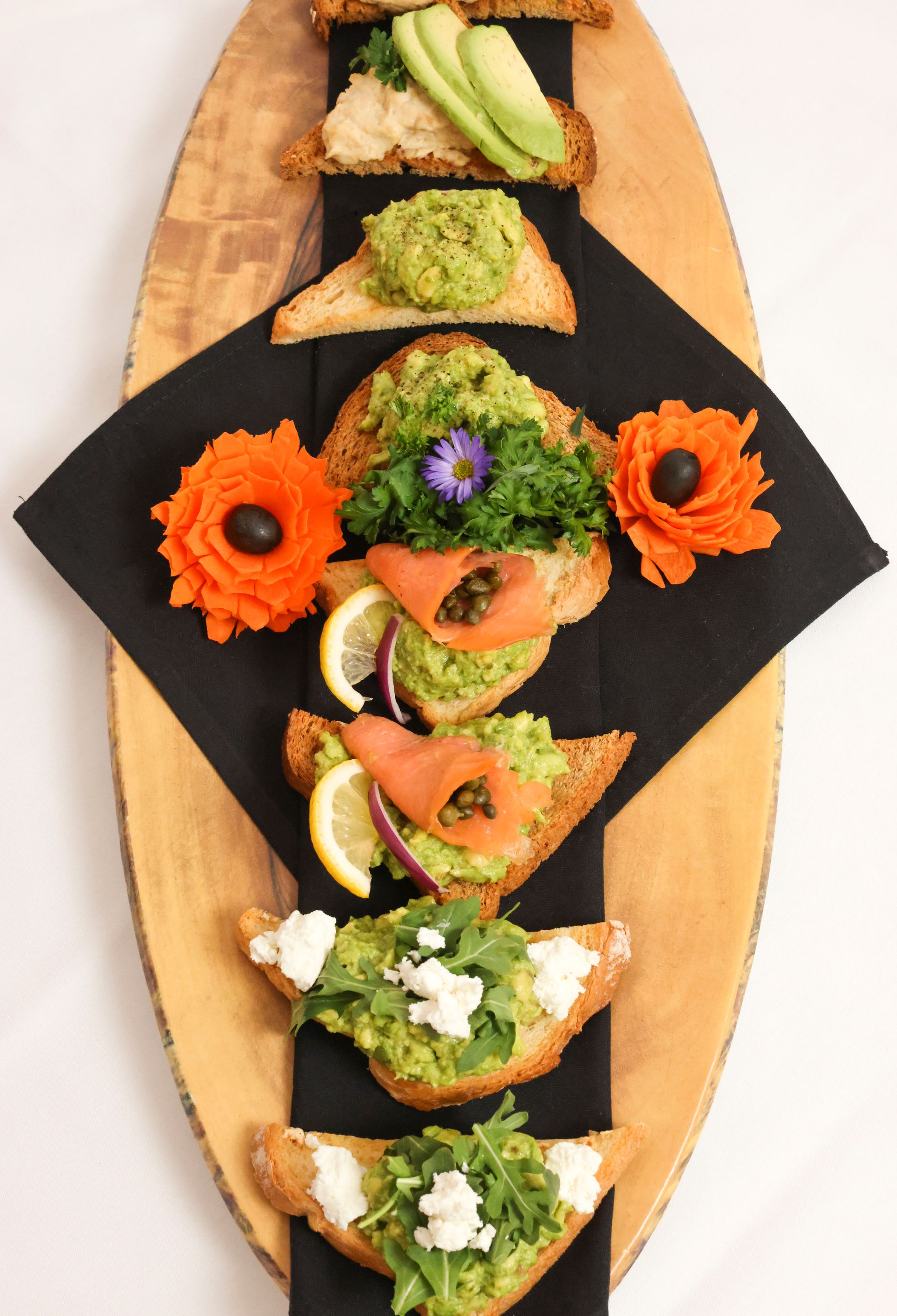 EQX City Catering Event Space at Rockefeller Center - A wooden cutting board with a variety of sandwiches on it