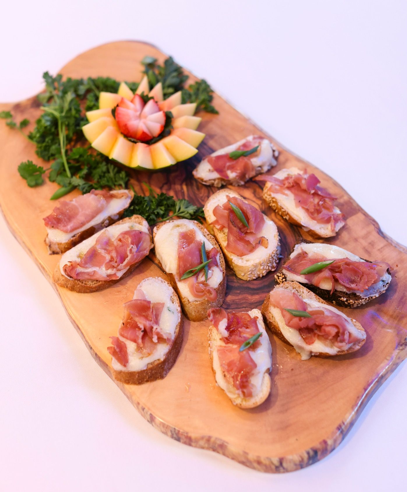 EQX City Catering at Rockefeller Center - A wooden cutting board topped with slices of meat and a strawberry