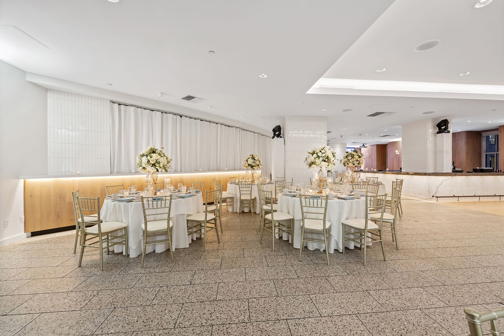 A large room with tables and chairs set up for a wedding reception.