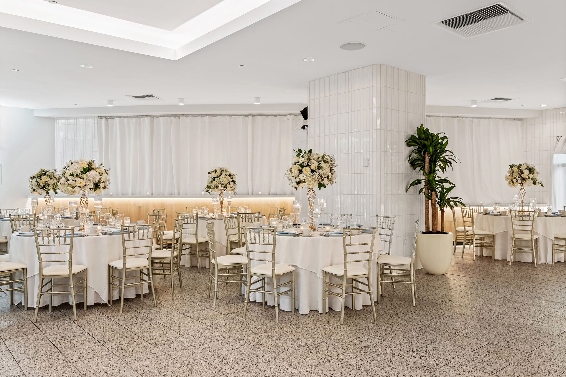 A large room with tables and chairs set up for a wedding reception.