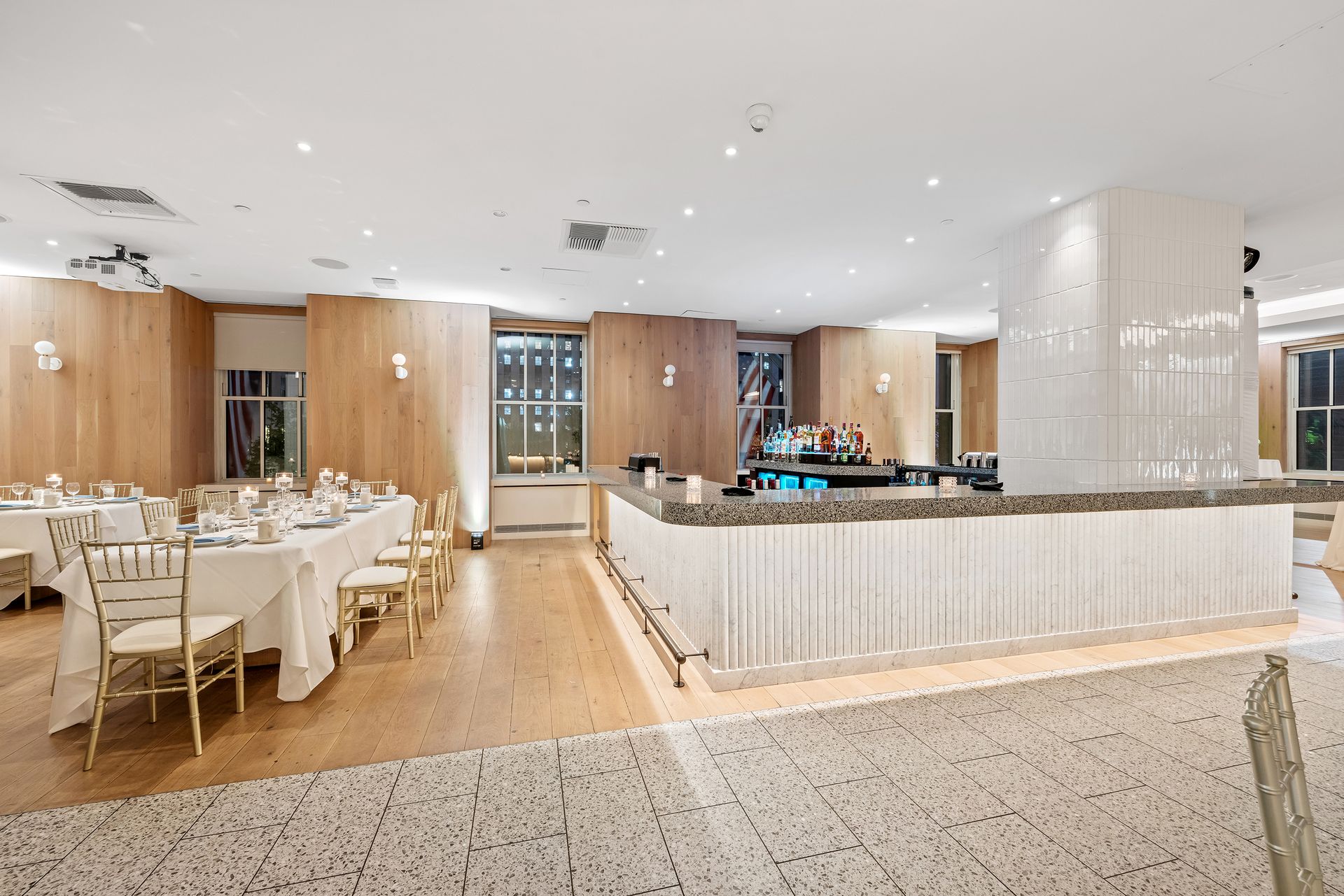 EQX City Catering at Rockefeller Center. A large room with tables and chairs and a bar.