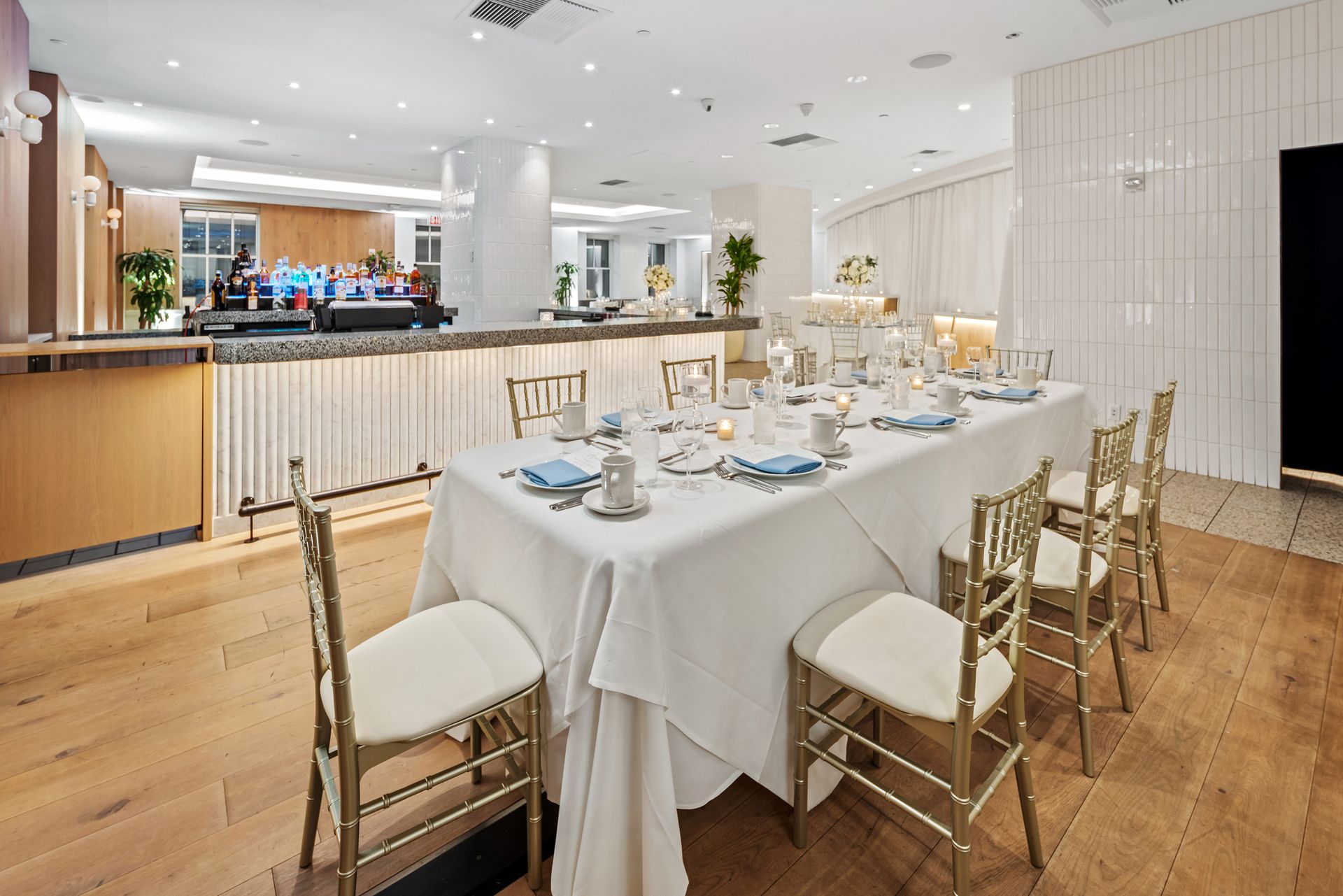 EQX City Catering at Rockefeller Center. A long table with a white tablecloth and chairs in a restaurant.