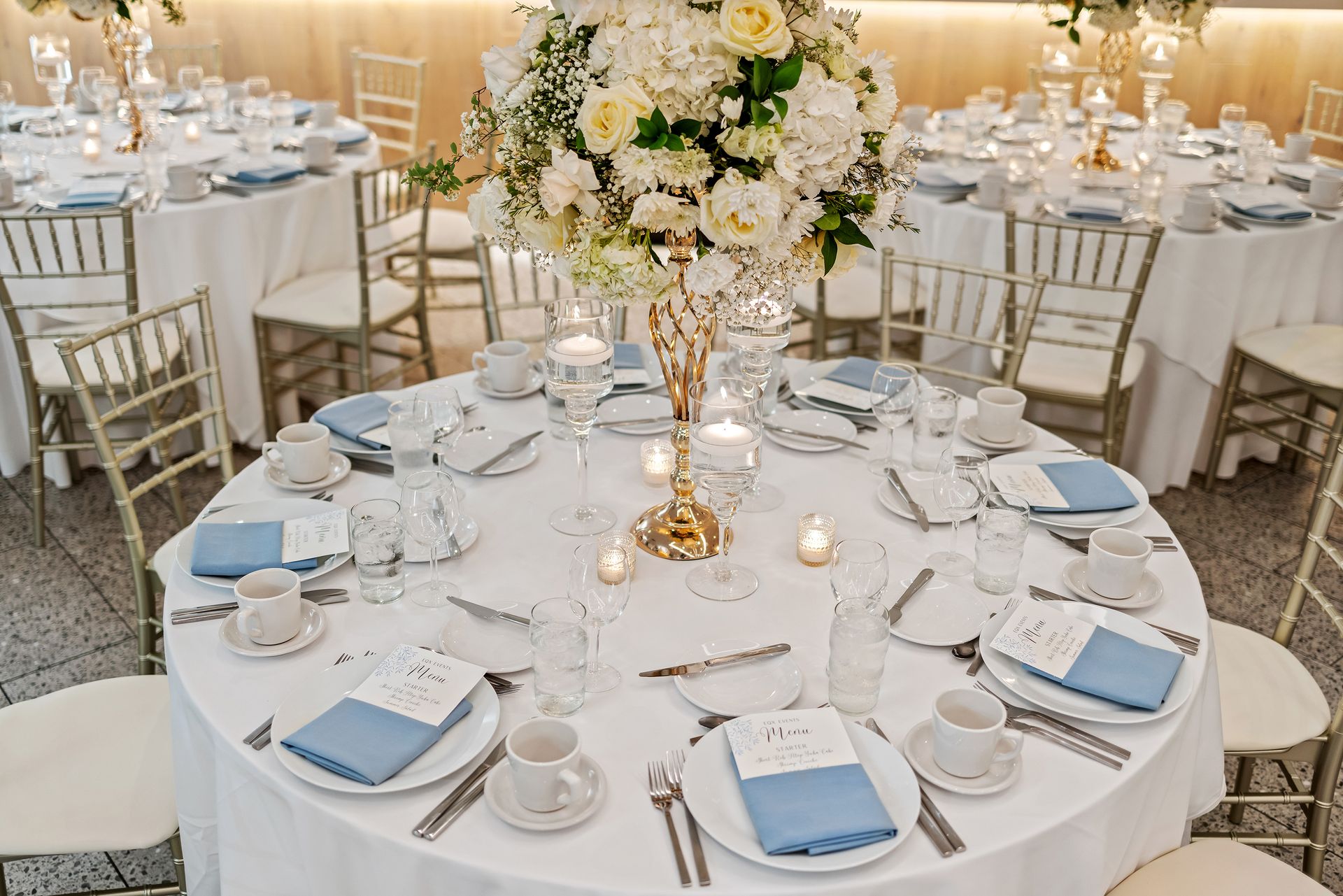 A table set for a wedding reception with a vase of flowers on it.