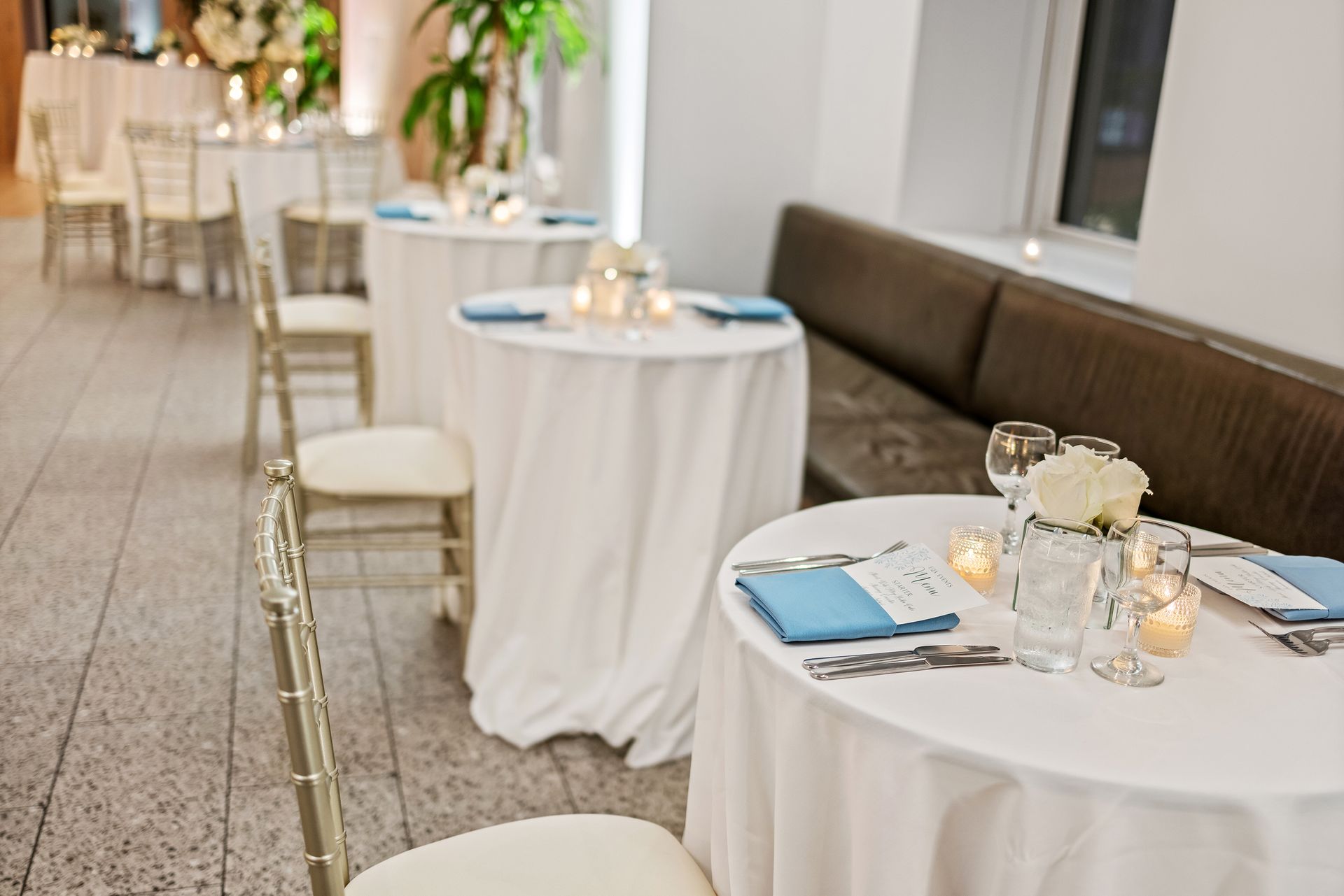 A room with tables and chairs set up for a wedding reception