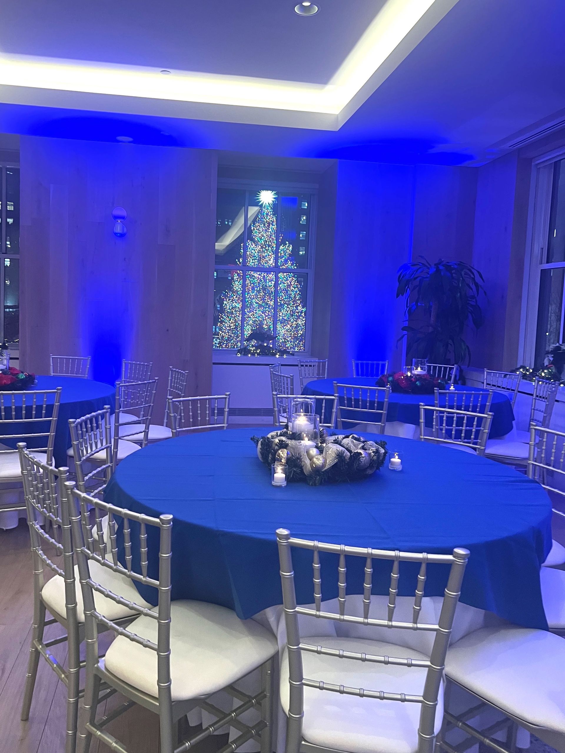 EQX City Catering Event Space at Rockefeller Center - A room with tables and chairs and a christmas tree in the background.