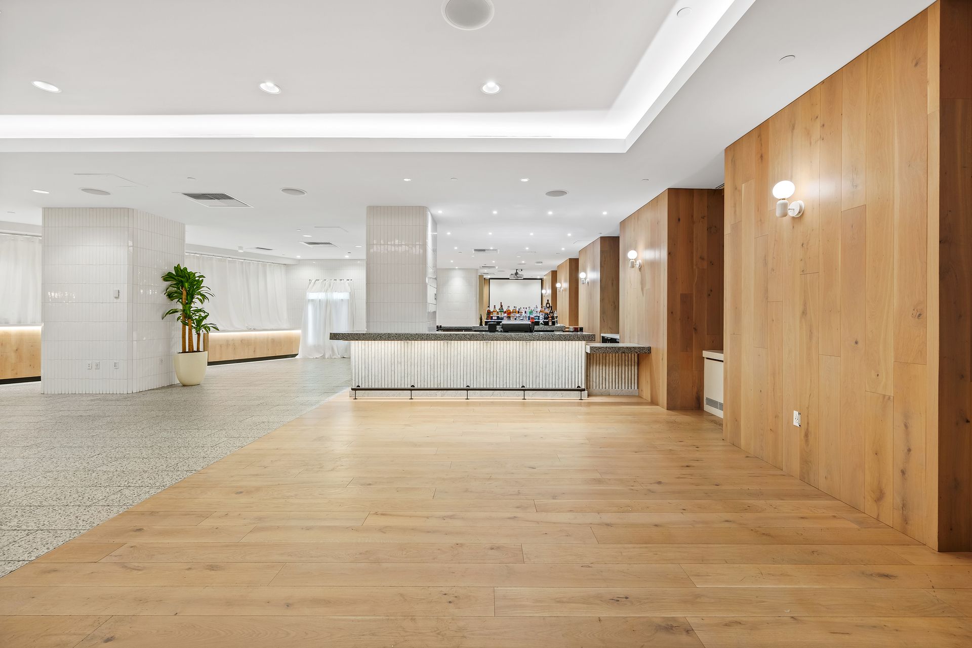 EQX City Catering Event Space at Rockefeller Center - A large empty lobby with wooden floors and a white counter.