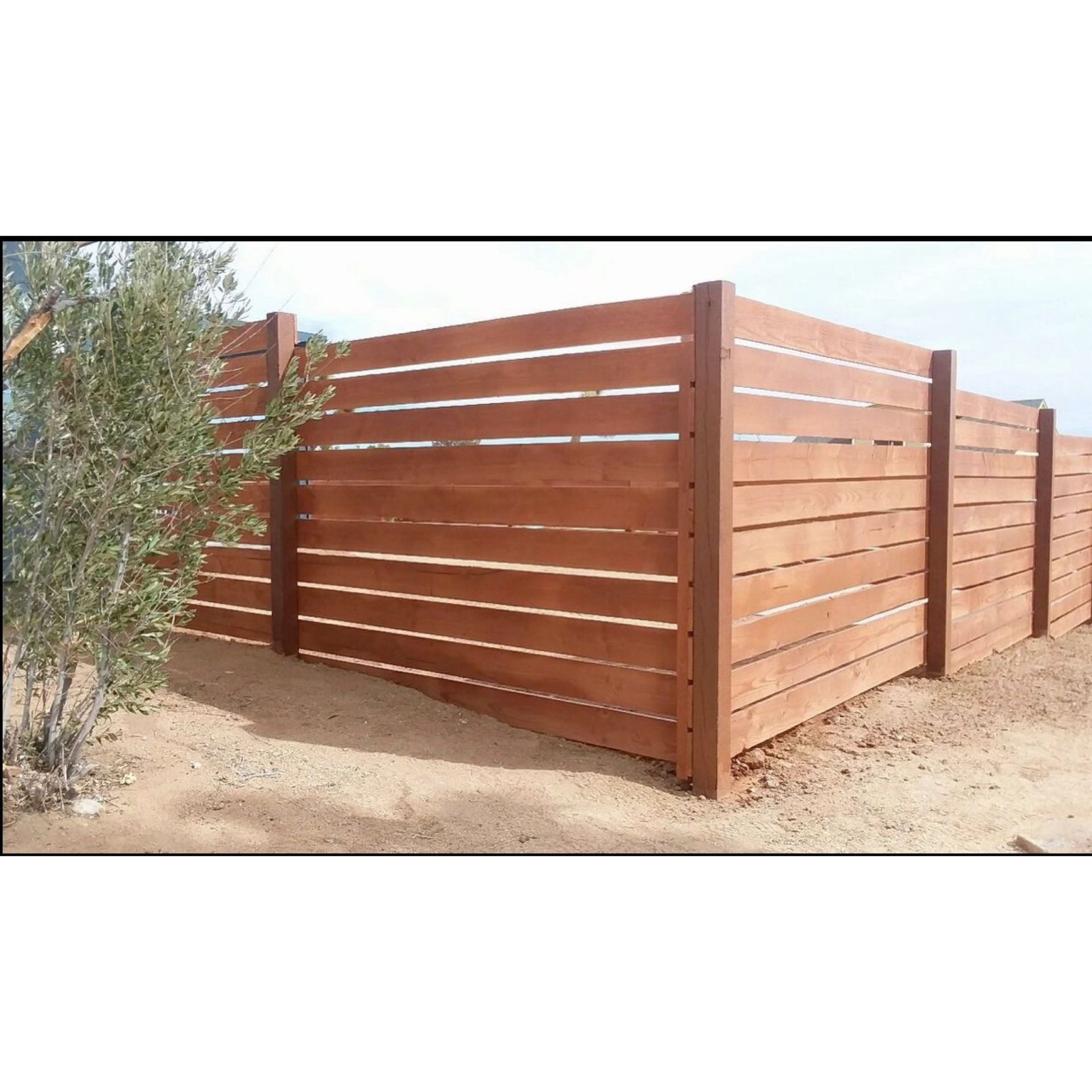 Wooden slat privacy fence enclosing a yard in a dry outdoor setting