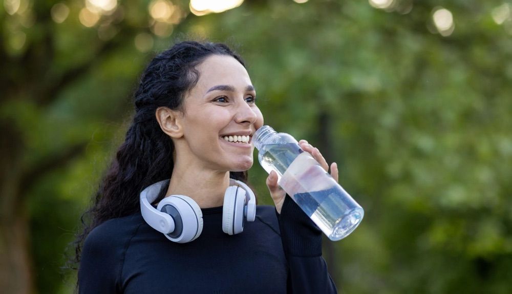 A woman drinking an electrolyte drink.