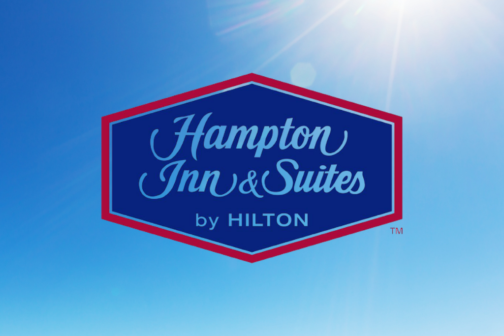 Hampton Inn & Suites by Hilton logo on a blue background with sunlight flare