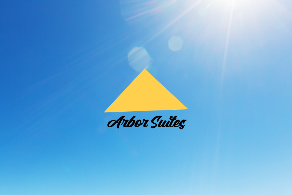 Arbor Suites logo with yellow triangle on a blue sky background and sun flare