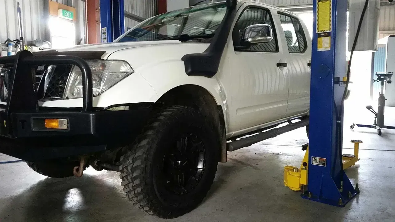 White Pickup Truck on a Lift in an Auto Repair Garage — Fischer Automotive in Svensson Heights, QLD