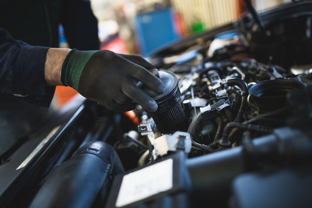 Gloved Hand Repairing a Car Engine in a Garage — Fischer Automotive in Svensson Heights, QLD