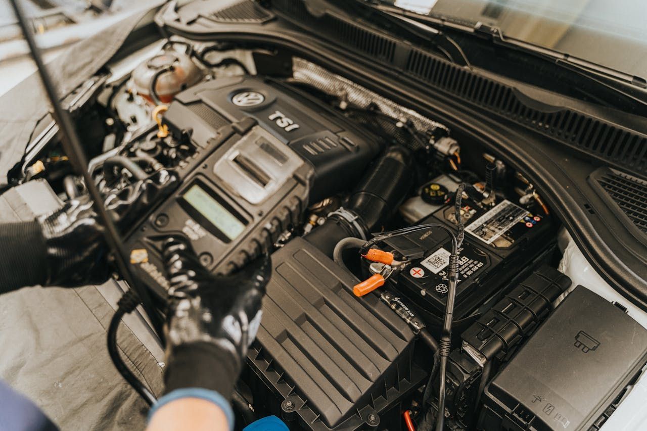 Mechanic Inspecting a Car Engine Bay With Battery — Fischer Automotive in Svensson Heights, QLD