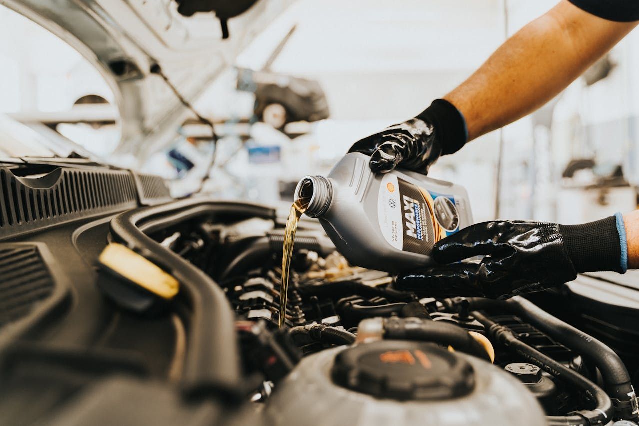 Mechanic Pouring Motor Oil Into an Engine Bay — Fischer Automotive in Svensson Heights, QLD