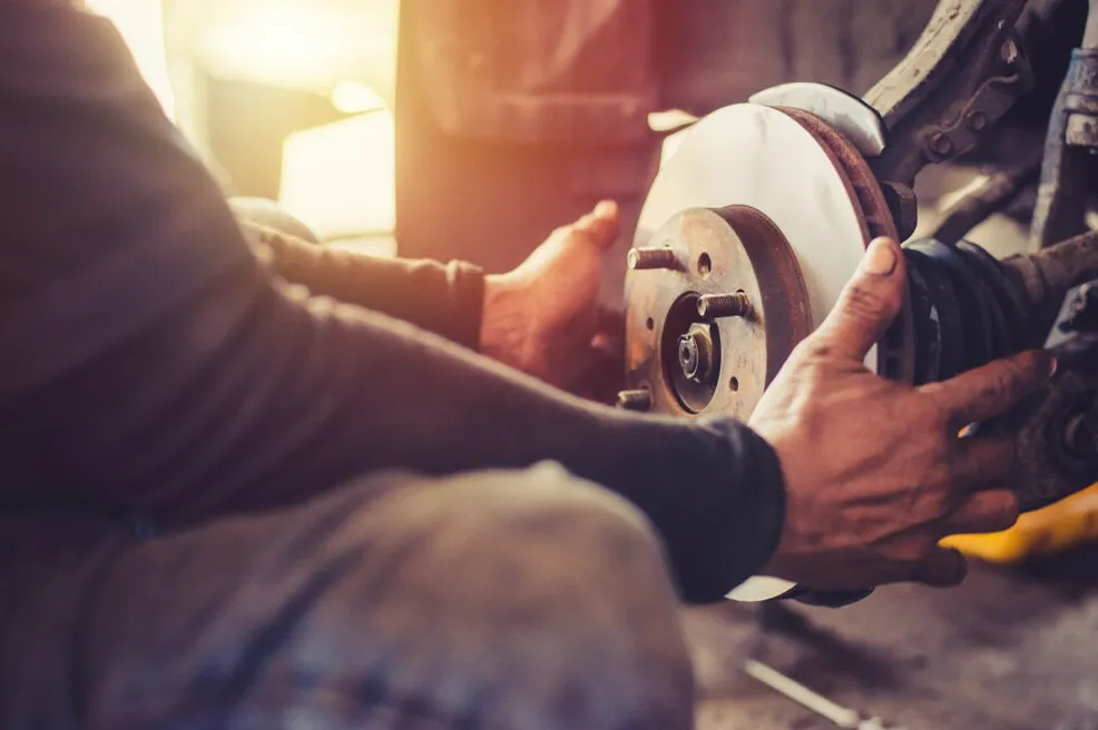 Hands Installing a Brake Disc on a Vehicle in a Garage — Fischer Automotive in Svensson Heights, QLD
