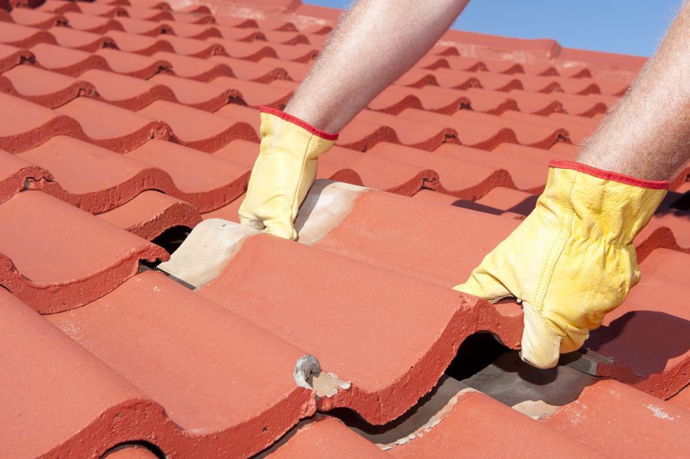 A Person Wearing Yellow Gloves is Working on a Roof — RJT Roofing In Bonner, ACT