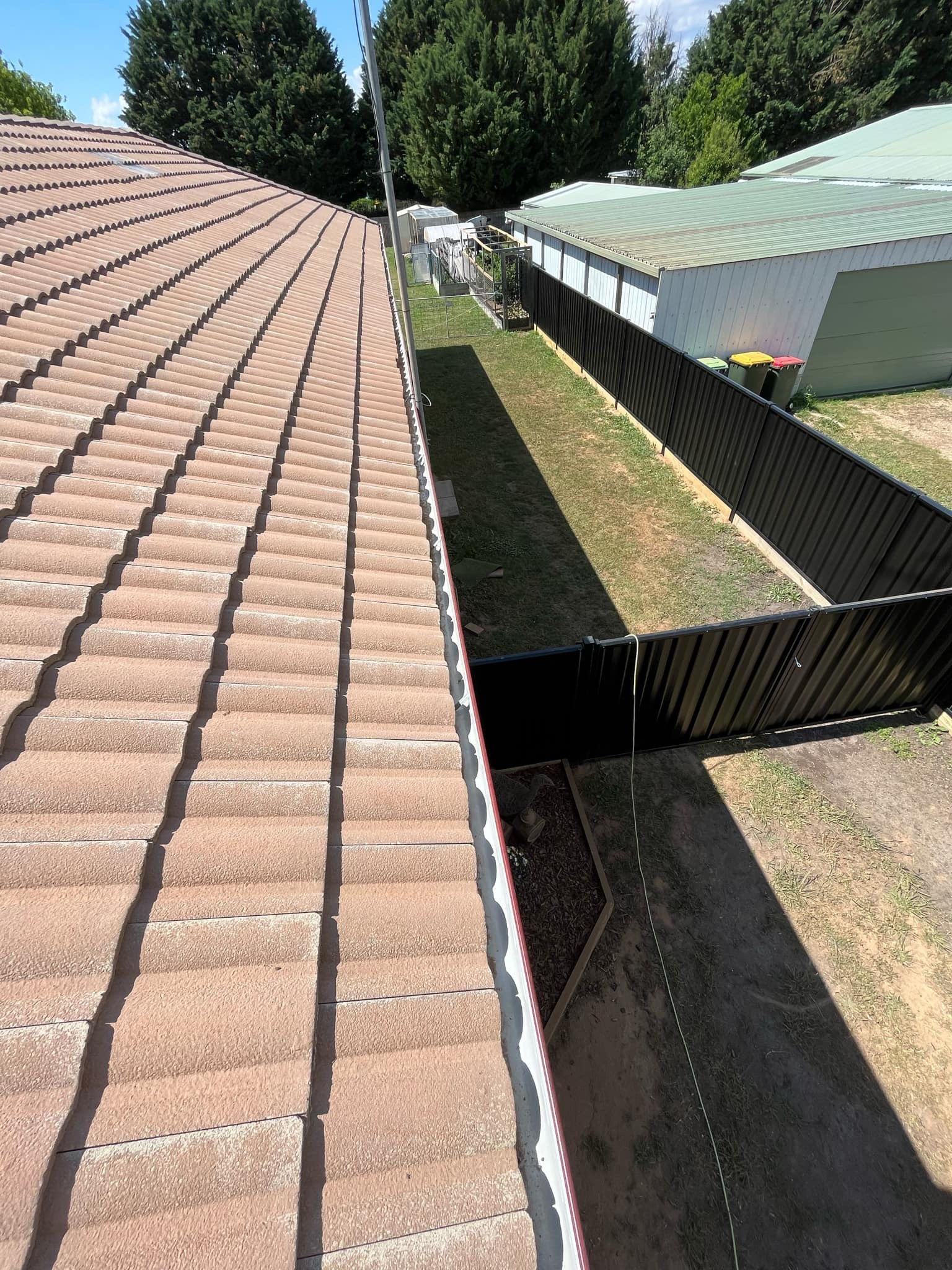 A gutter on the roof of a house with trees in the background — RJT Roofing In Gungahlin, ACT
