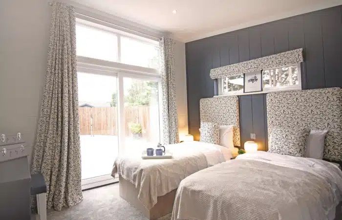 A bedroom with two twin beds and a large window.