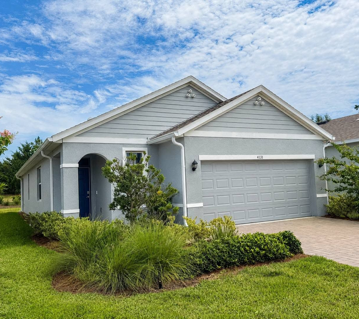 Single-story gray house with white trim, a two-car garage, and a landscaped front yard under a blue sky
