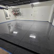 Empty garage with glossy gray floor coating and wall-mounted bike rack in the background