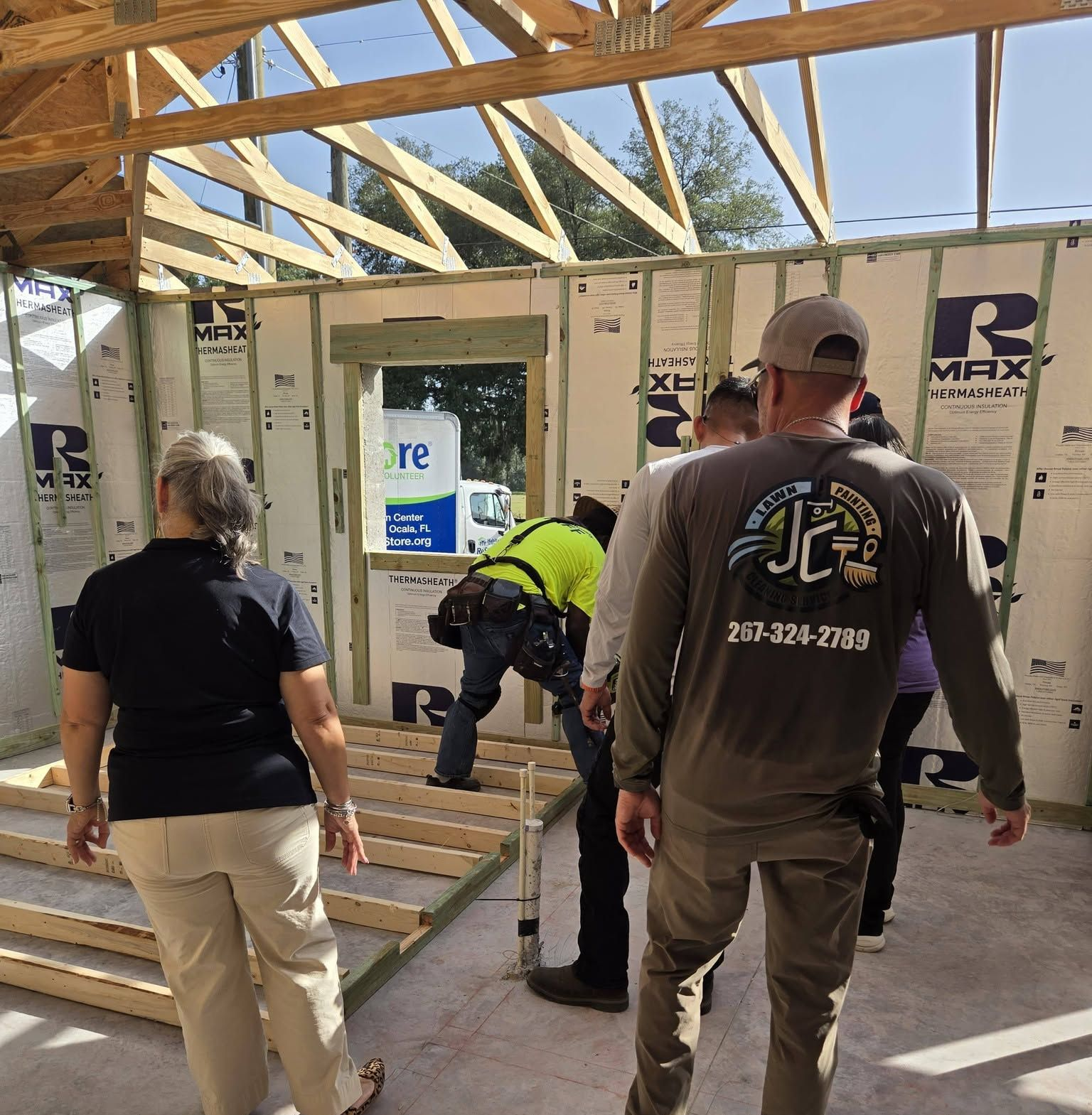 Workers framing a house interior under construction, with exposed wood beams and insulation panels.