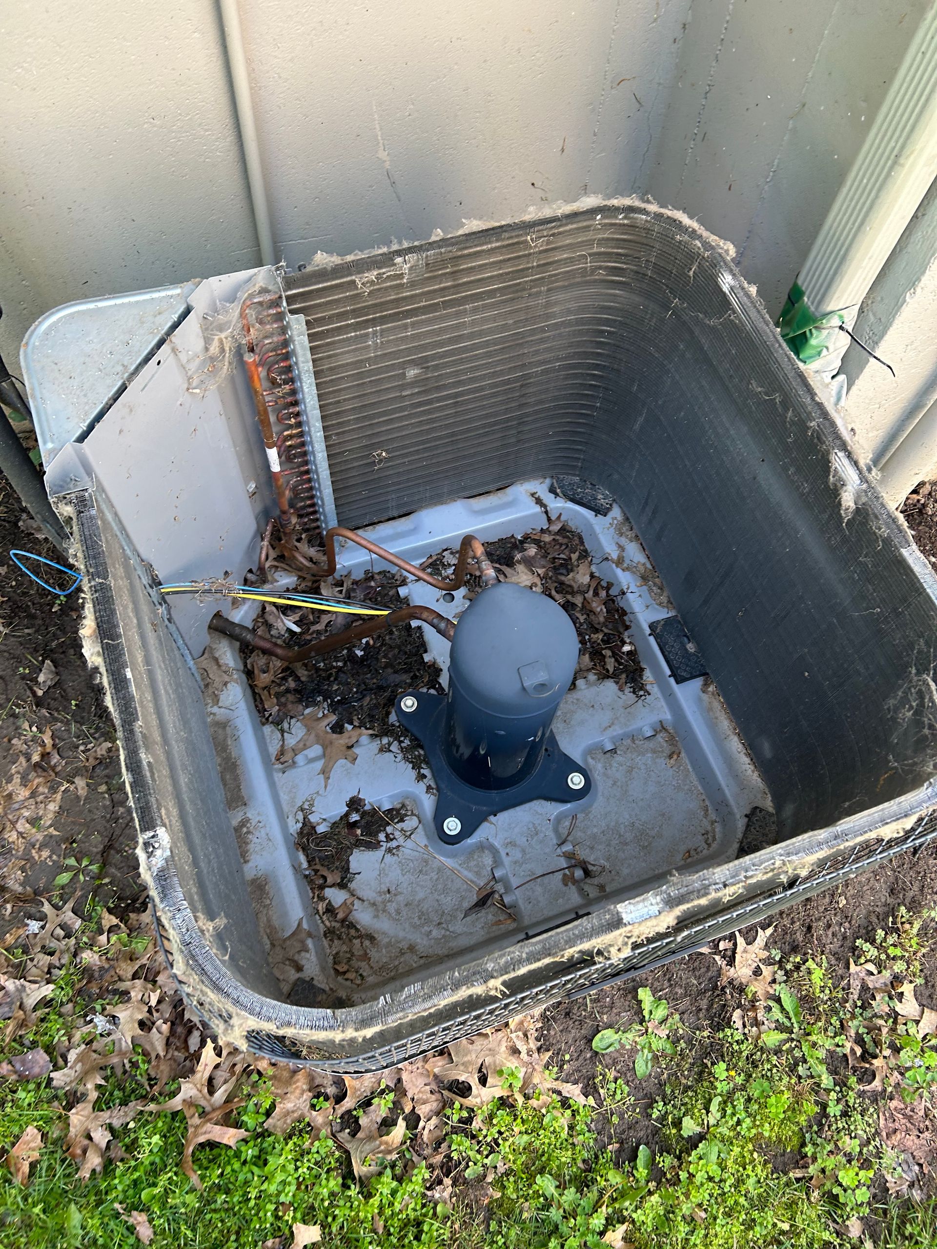 A dirty air conditioner is sitting on the ground next to a wall.