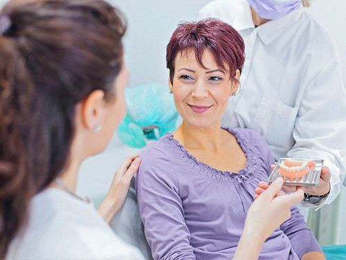 a woman is getting her teeth examined by two dentists in a dental office .