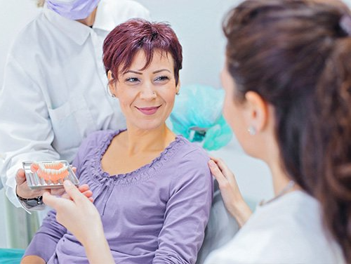 a woman is sitting in a dental chair talking to a dentist .