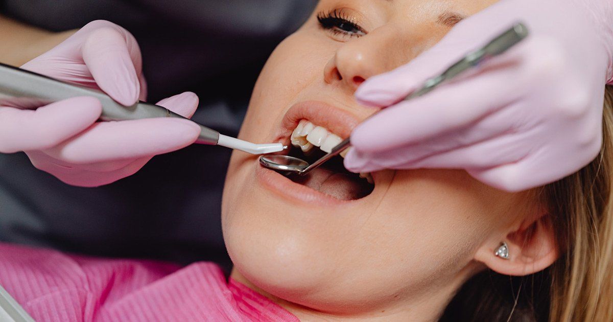 a woman is getting her teeth examined by two dentists in a dental office .