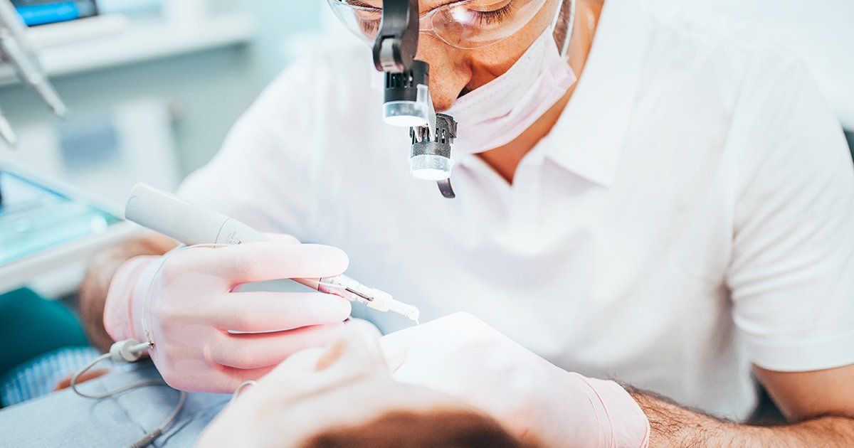 a dentist is examining a patient 's teeth with a magnifying glass .