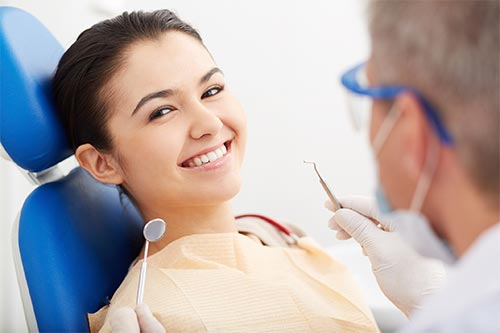 a woman is sitting in a dental chair while a dentist examines her teeth .
