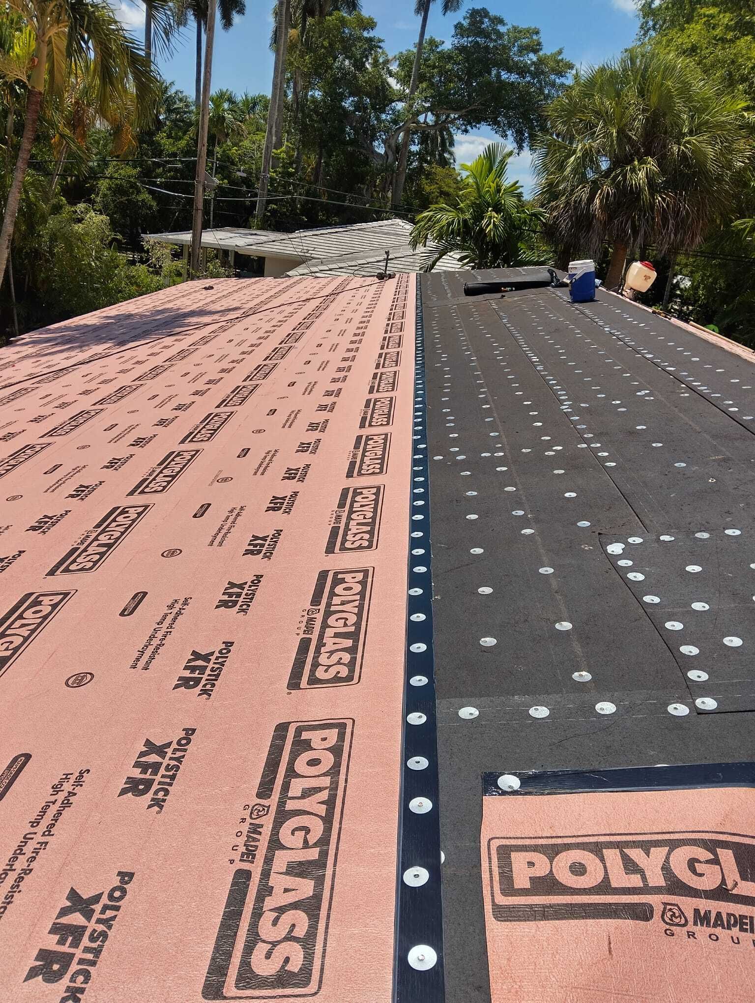 Roof under construction with pink underlayment on one side and black on the other.