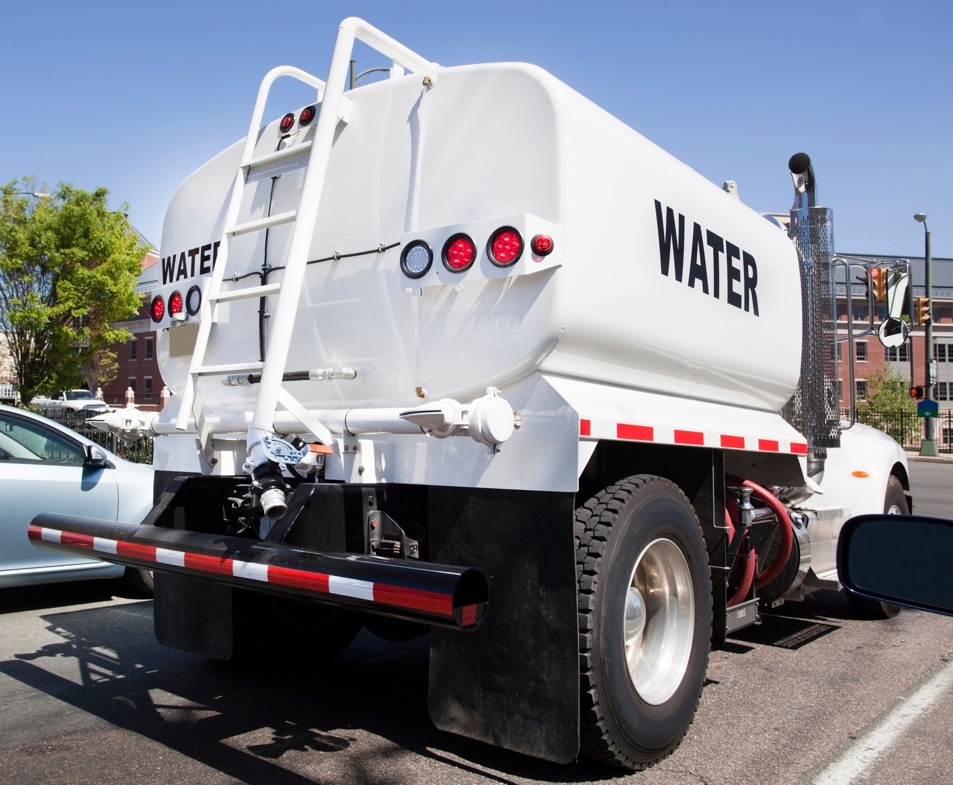 Rear view of a white water tanker truck parked in a sunny lot. Rear view of a white water tanker truck parked in a sunny lot.