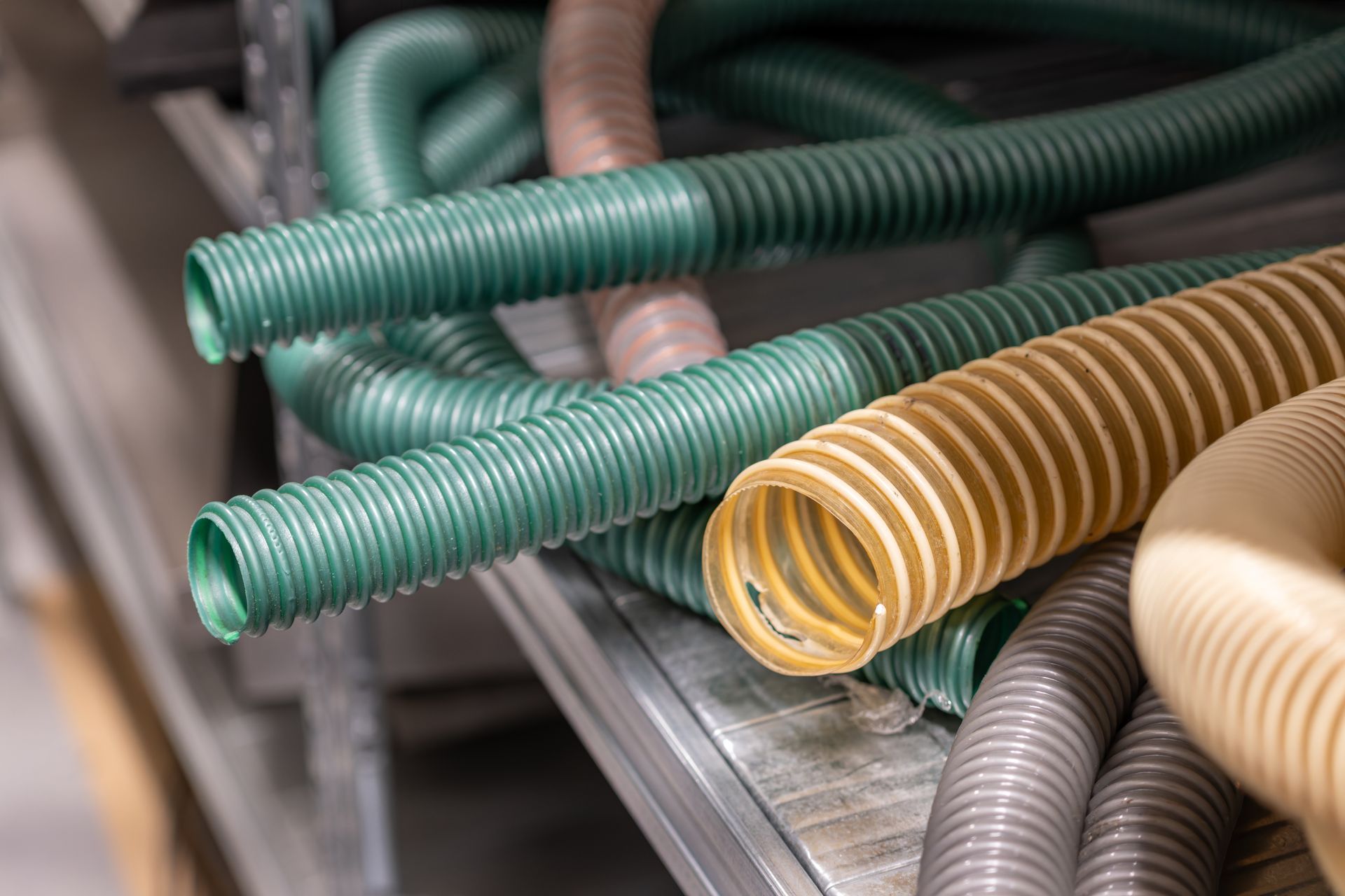 Flexible corrugated hoses and tubing stacked on a metal shelf in a plumbing supply area. Flexible corrugated hoses and tubing stacked on a metal shelf in a plumbing supply area.