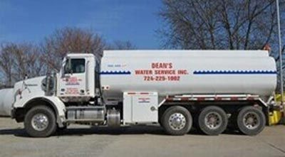 A white water service tanker truck parked on pavement with company branding and phone number visible A white water service tanker truck parked on pavement with company branding and phone number visible