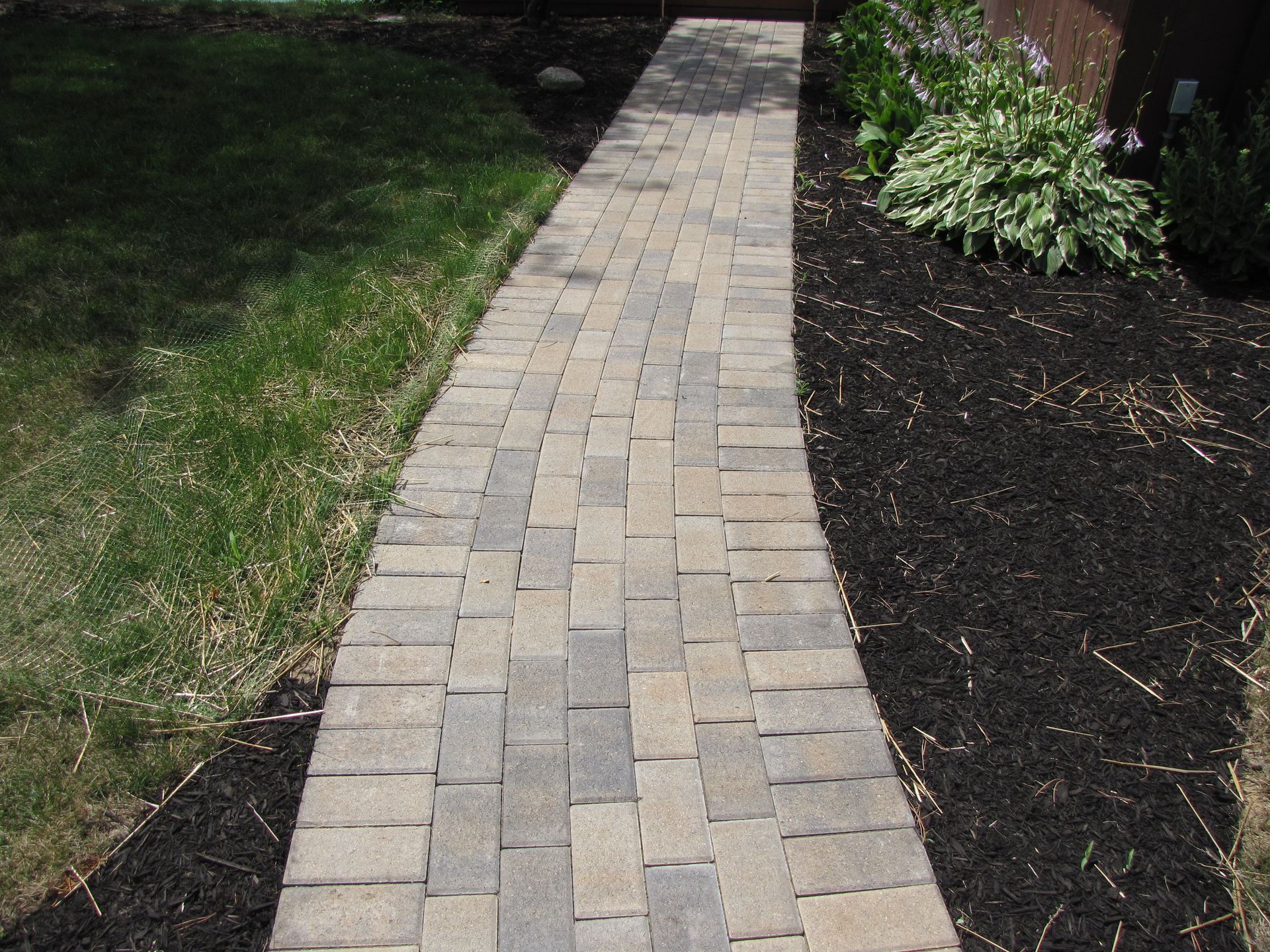 A brick walkway leading to a house with stairs