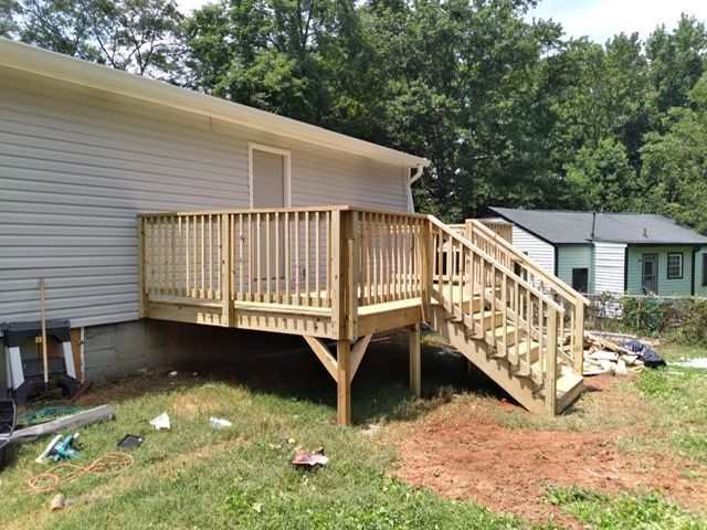 Wooden porch and stairs added to the side of a white house in a grassy yard