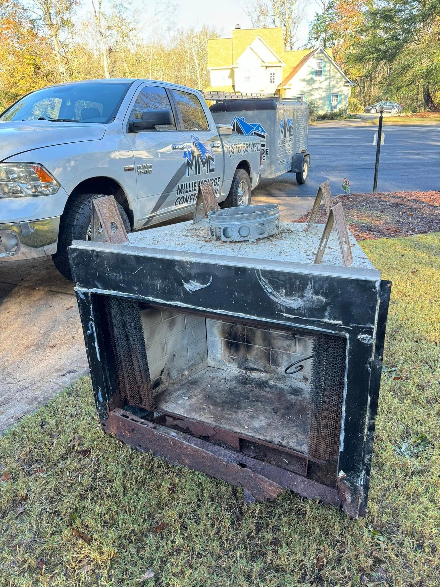 Overturned black metal dumpster on a lawn beside a silver pickup truck and suburban street