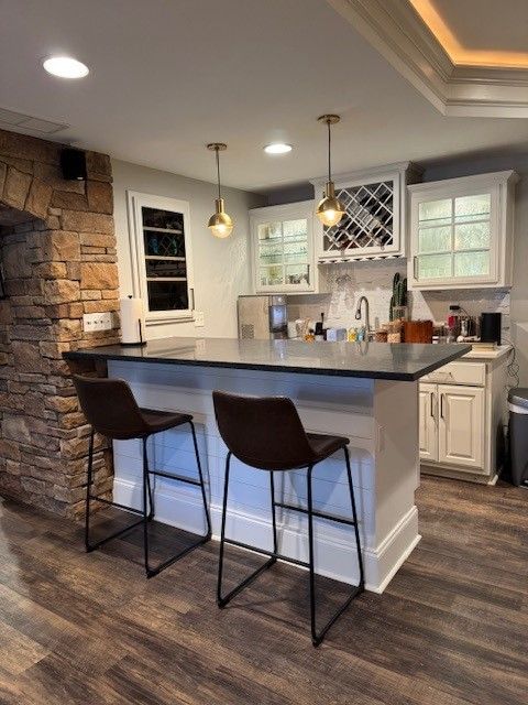 Modern kitchen with stone accent wall, gray island, pendant lights, and two bar stools