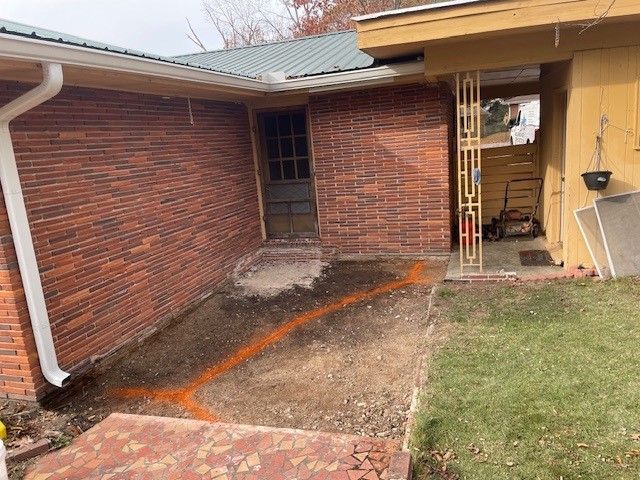 Brick walkway and porch ramp leading to a house entrance beside a lawn