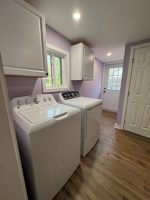 Laundry room with white washer and dryer, lavender walls, and a window.