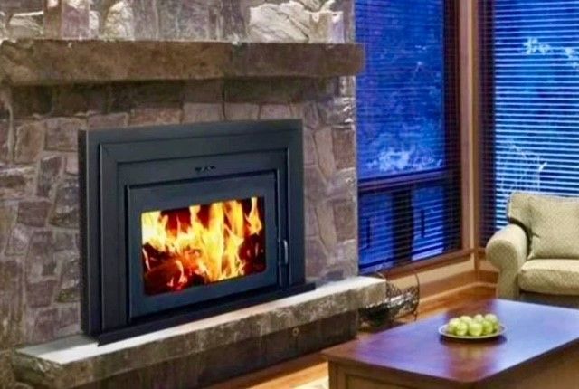 Stone fireplace with a lit fire beside a window, sofa, and coffee table in a cozy living room