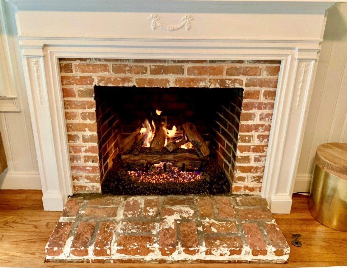 Lit brick fireplace with burning logs and a white mantel in a living room