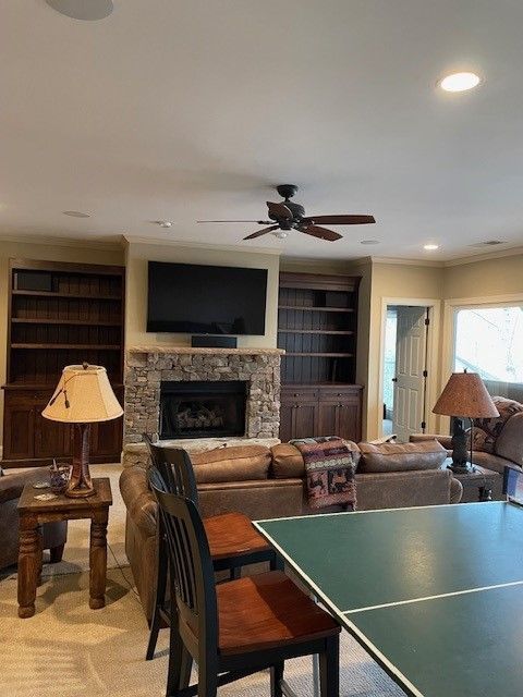 Cozy living room with fireplace, wall-mounted TV, built-ins, and a ping-pong table in front
