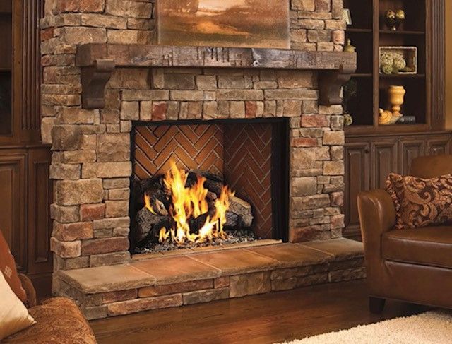 Stone fireplace with a roaring fire in a cozy living room, surrounded by rustic decor and leather furniture
