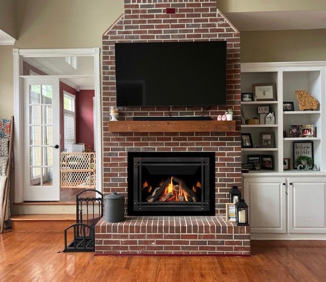 Living room with brick fireplace, wall-mounted TV, and built-in white shelves on either side